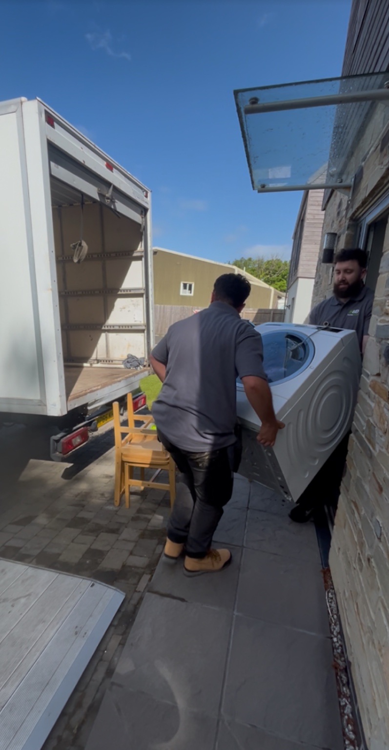 Hauling & Disposal team moving a washing machine beside a Luton van